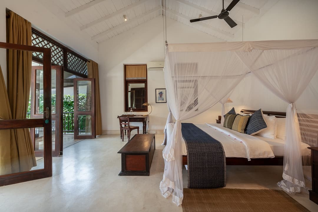 Villa king bedroom with timber ceiling fan and tropical garden view in Galle Fort
