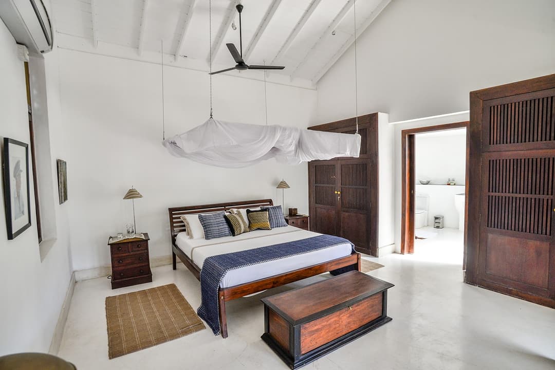 Villa king bedroom with timber shuttered door and blue stripe textile in Galle Fort