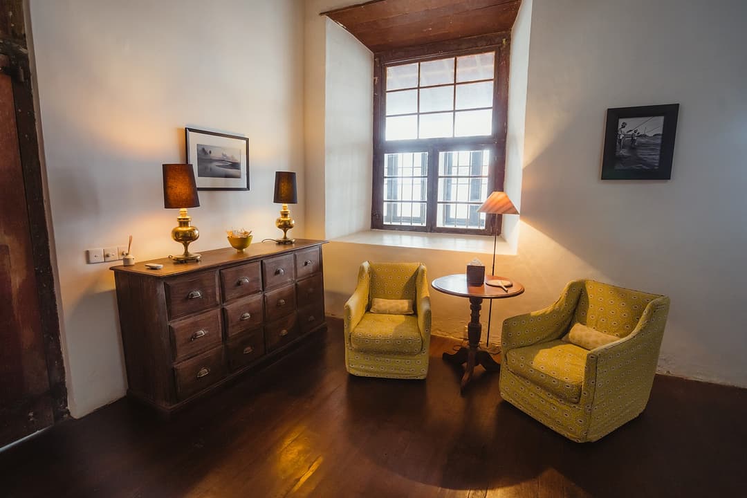 Villa sitting room with yellow armchairs and dark timber furniture inside Galle Fort