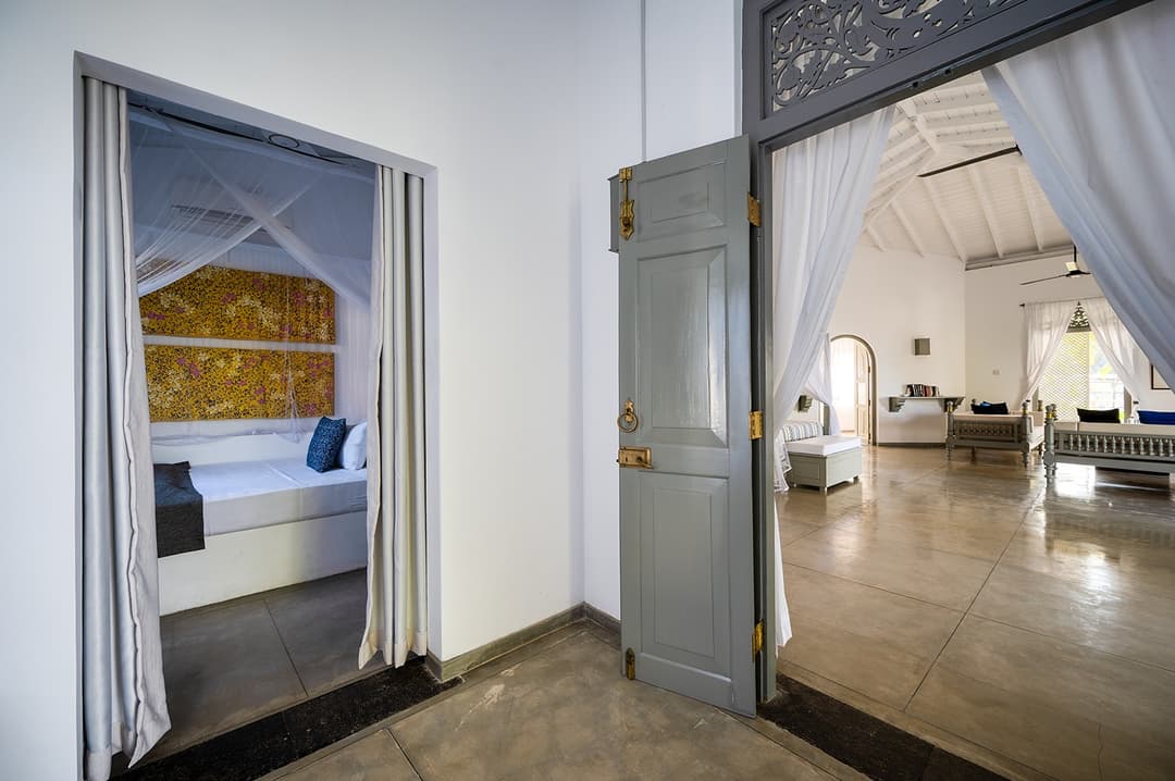 Beachfront villa bedroom with four-poster bed and arched doorway Unawatuna