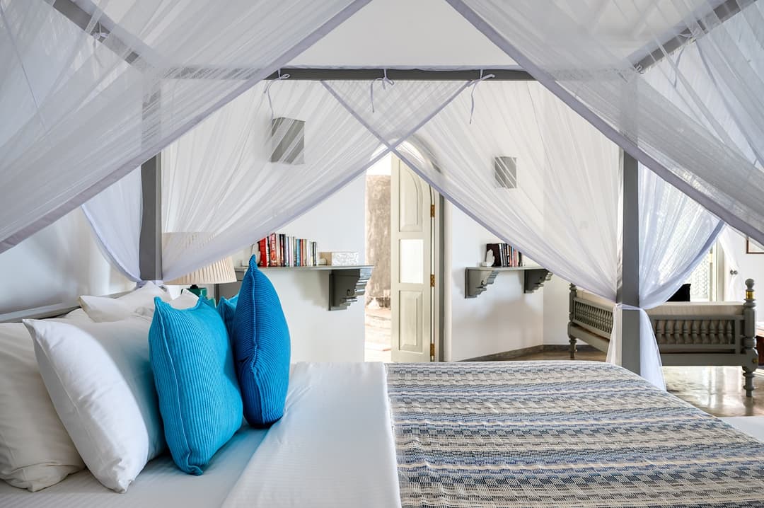 Beachfront villa bedroom with four-poster bed and blue cushions Unawatuna