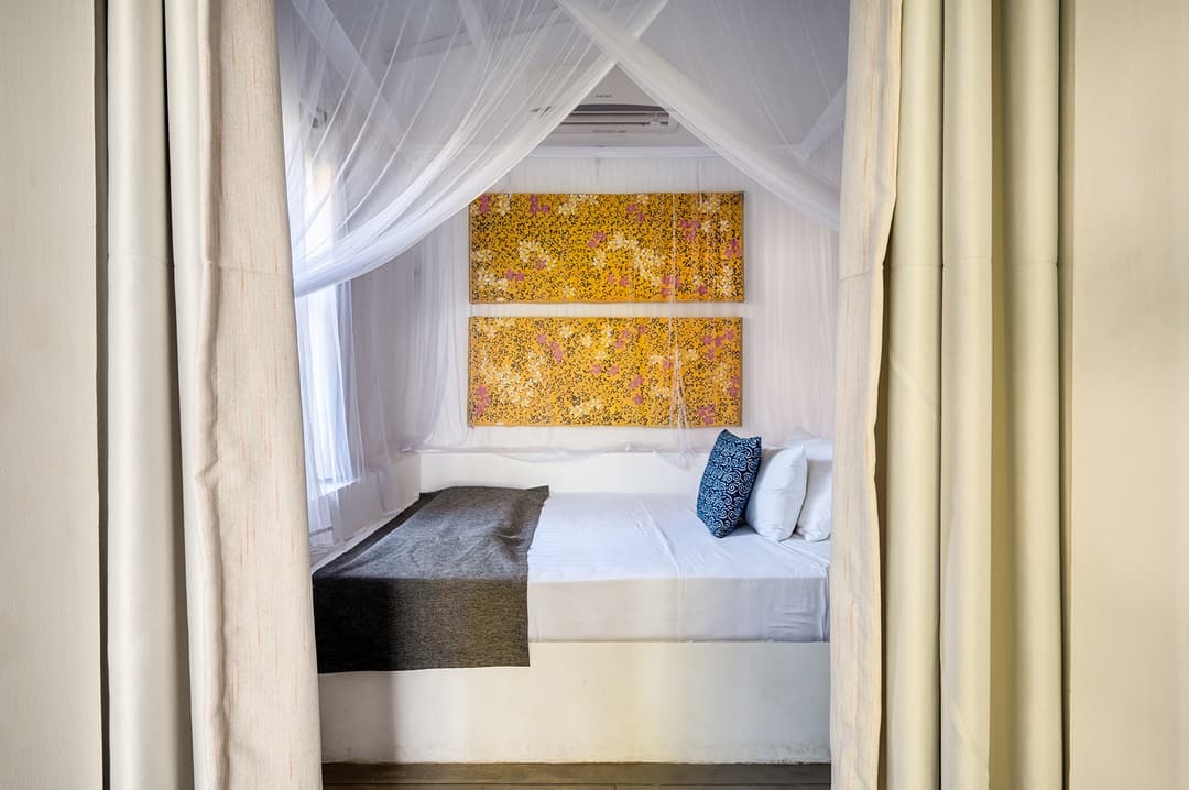 Beachfront villa bedroom with four-poster bed and gold panel headboard
