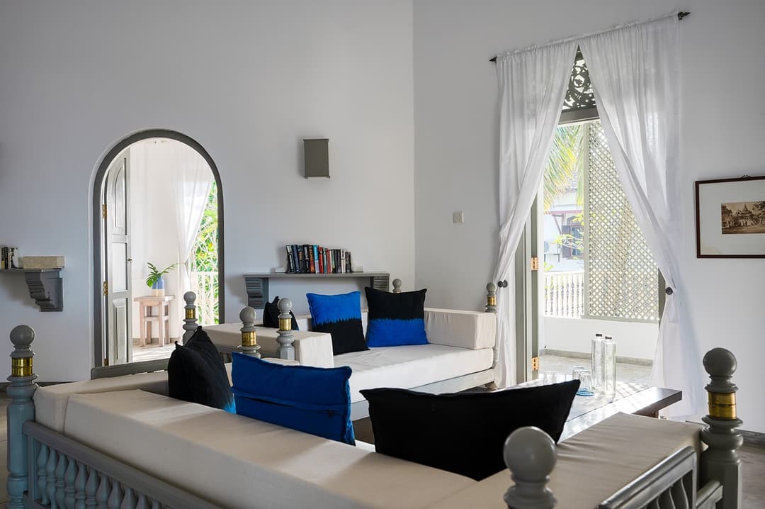 Beachfront villa bedroom with gold artwork panel and curtained four-poster bed
