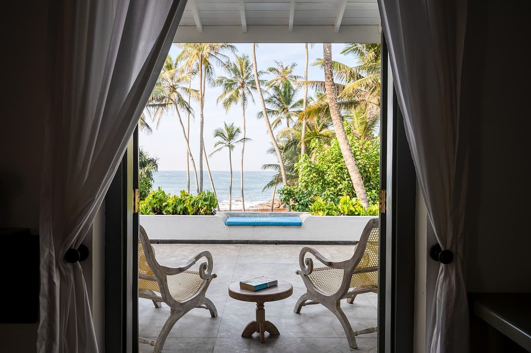 Beachfront villa bedroom with ocean view balcony and billowing curtains Unawatuna