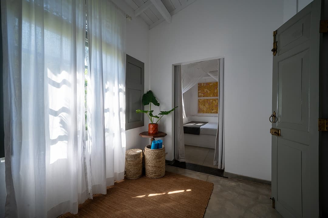 Beachfront villa bedroom with white curtains and sitting area Unawatuna Sri Lanka