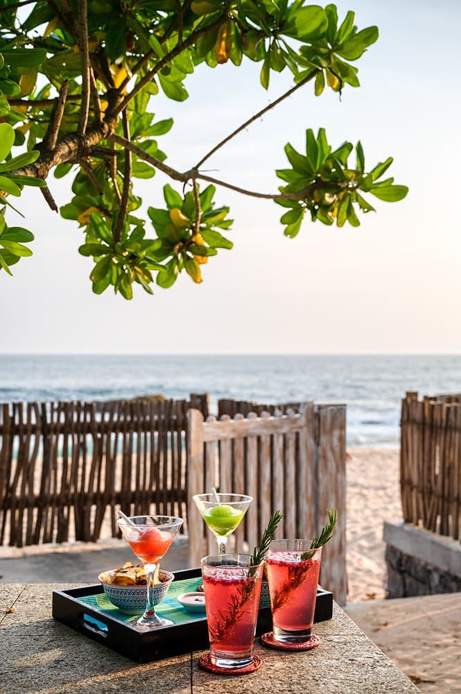 Beachfront villa cocktails on beach table with thatched fence Unawatuna Sri Lanka