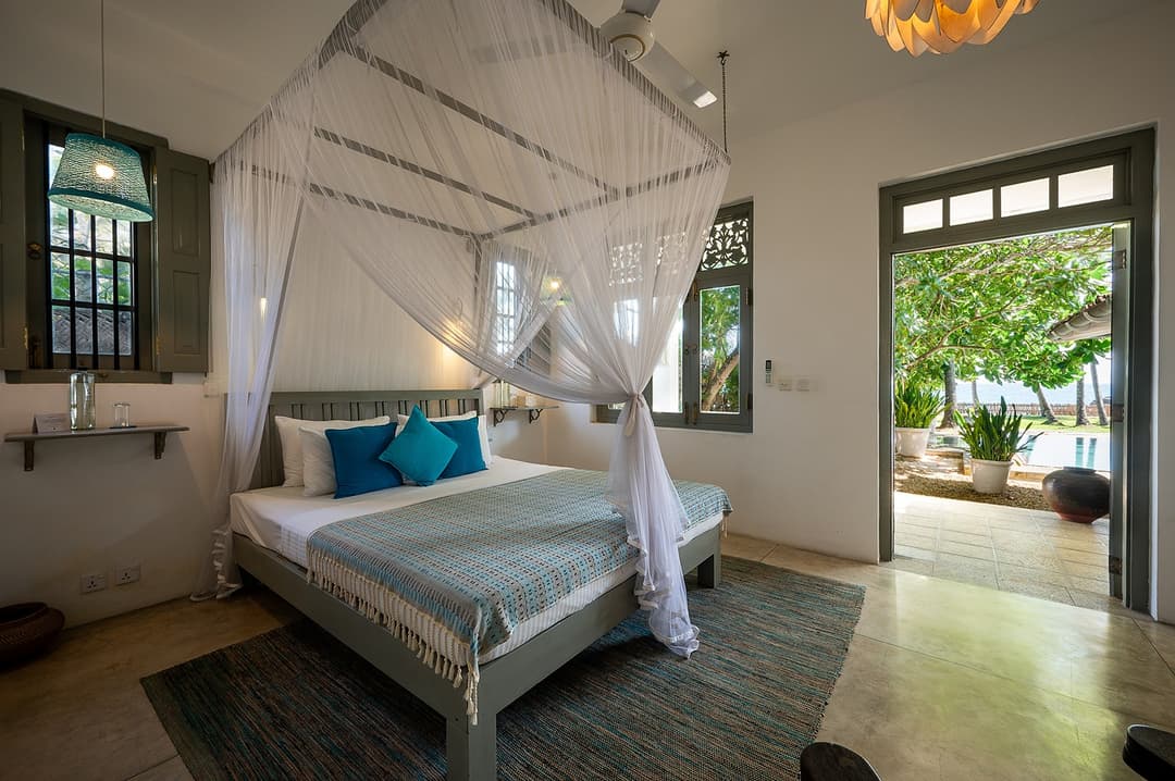Beachfront villa master bedroom with four-poster bed and chandelier Unawatuna