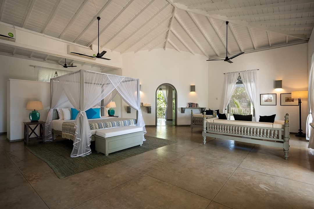 Beachfront villa master suite with four-poster bed opening to ocean view Unawatuna