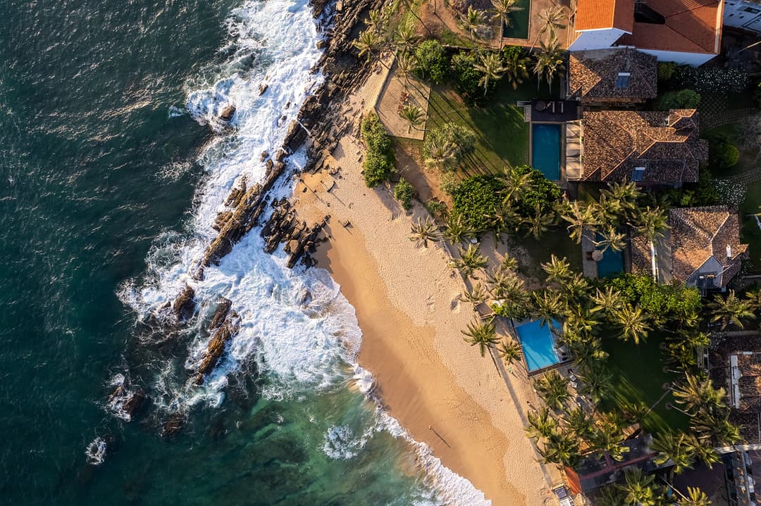 Aerial view of Villa Bleu Unawatuna on rocky beach with coconut palm trees
