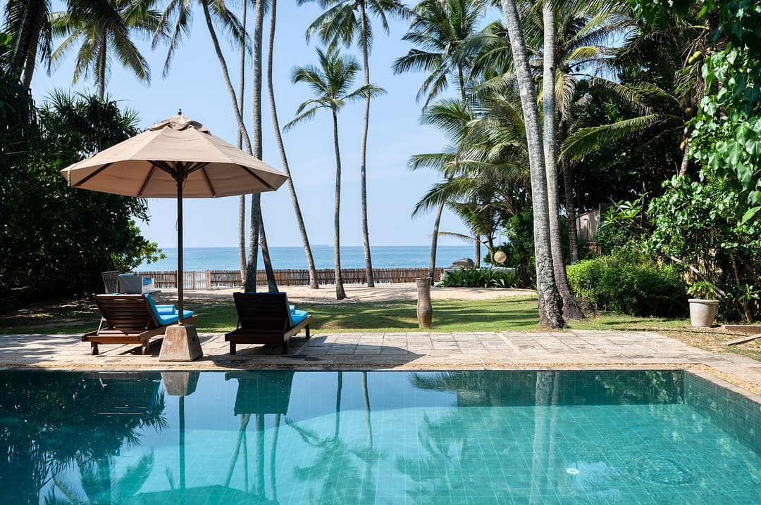 Villa Bleu Unawatuna pool with thatched umbrella and coconut palms and ocean