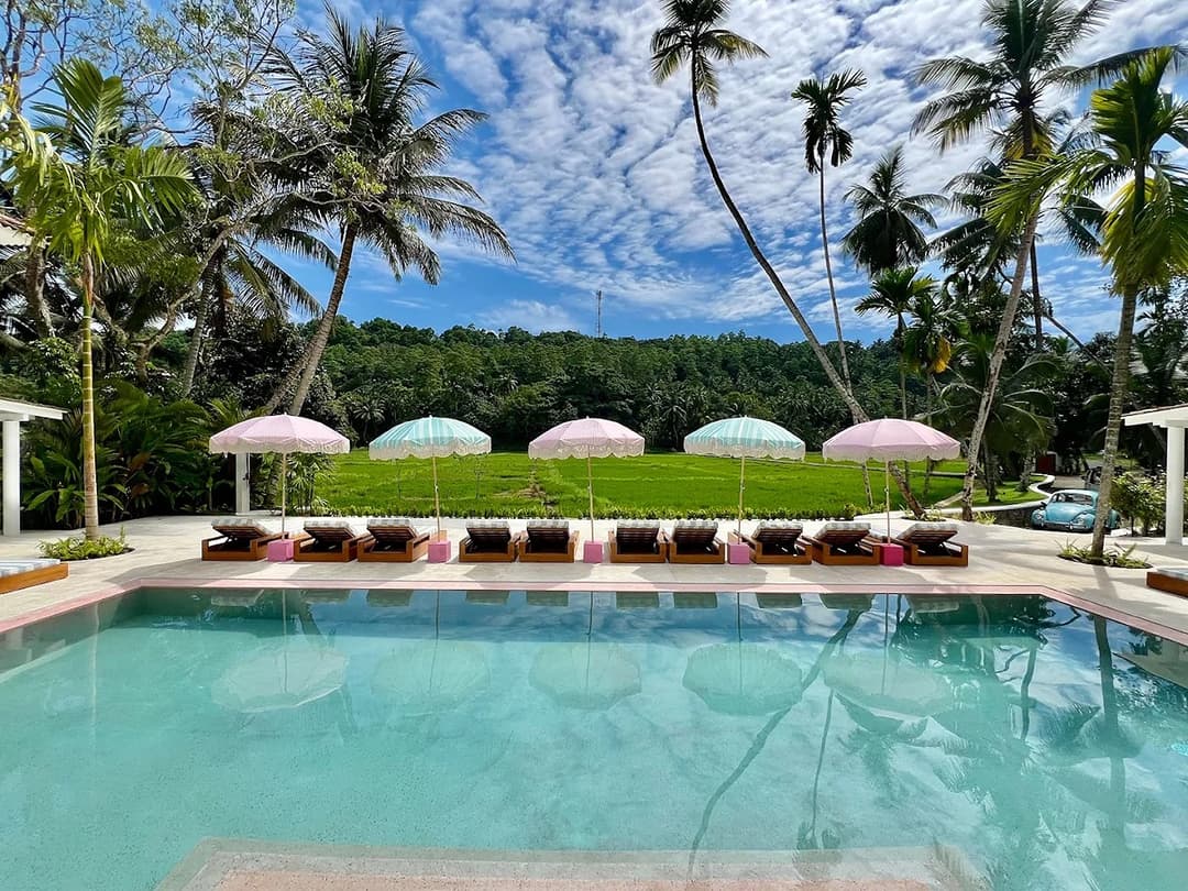Miss Ceylon Unawatuna pool with sun loungers and tropical garden under blue sky