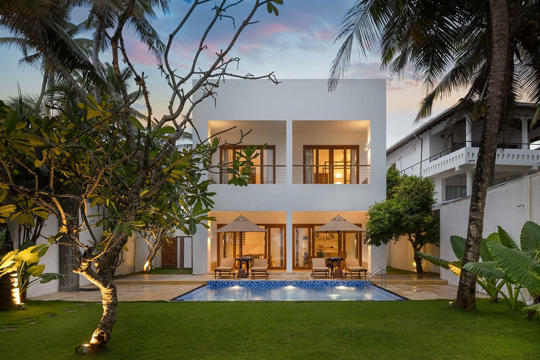 Verde Ahangama exterior pool and garden with villa illuminated at evening