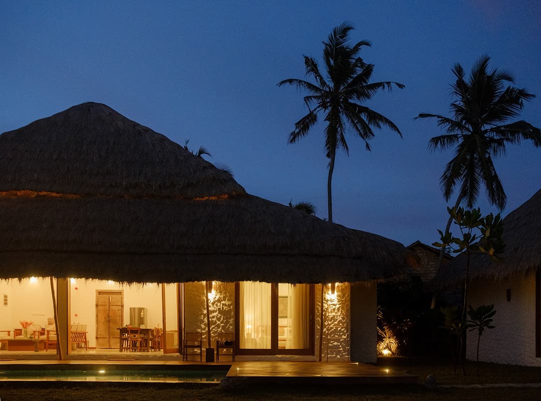 Boho House Mirissa exterior illuminated at evening with thatched roof