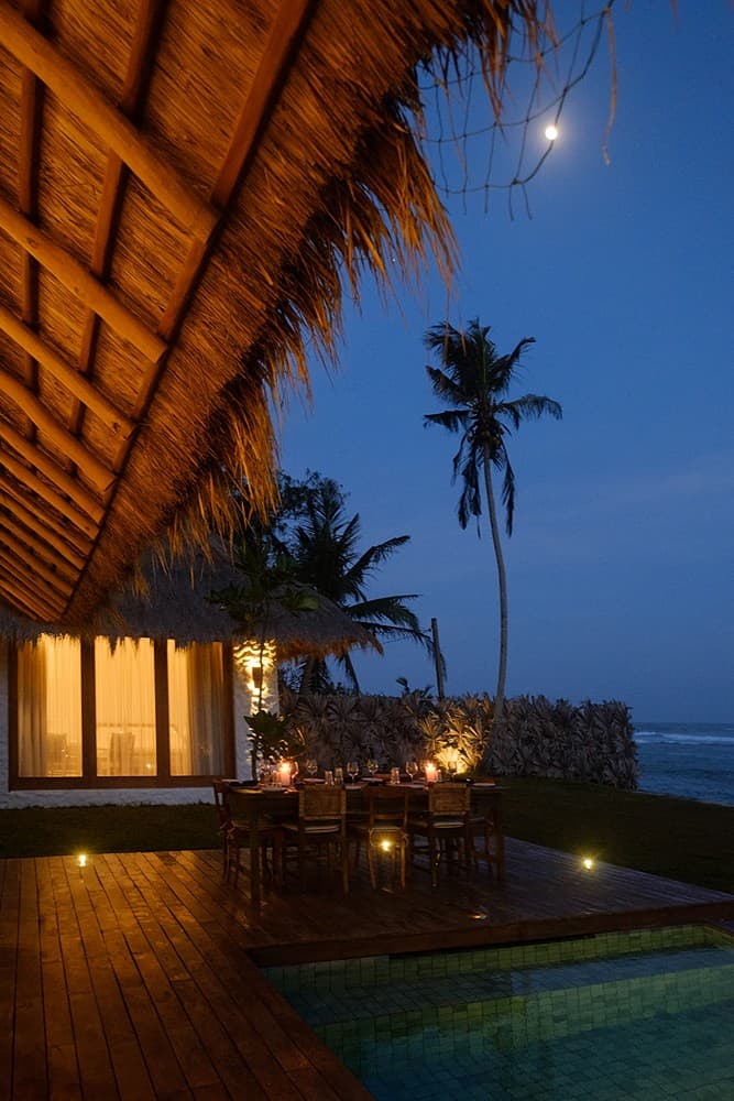 Boho House Mirissa thatched roof exterior at night with moonlight and palm