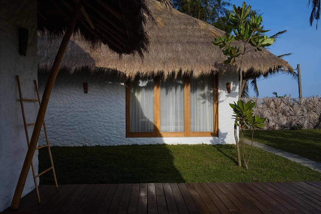 Close view of Boho House Mirissa thatched roof exterior with palm trees