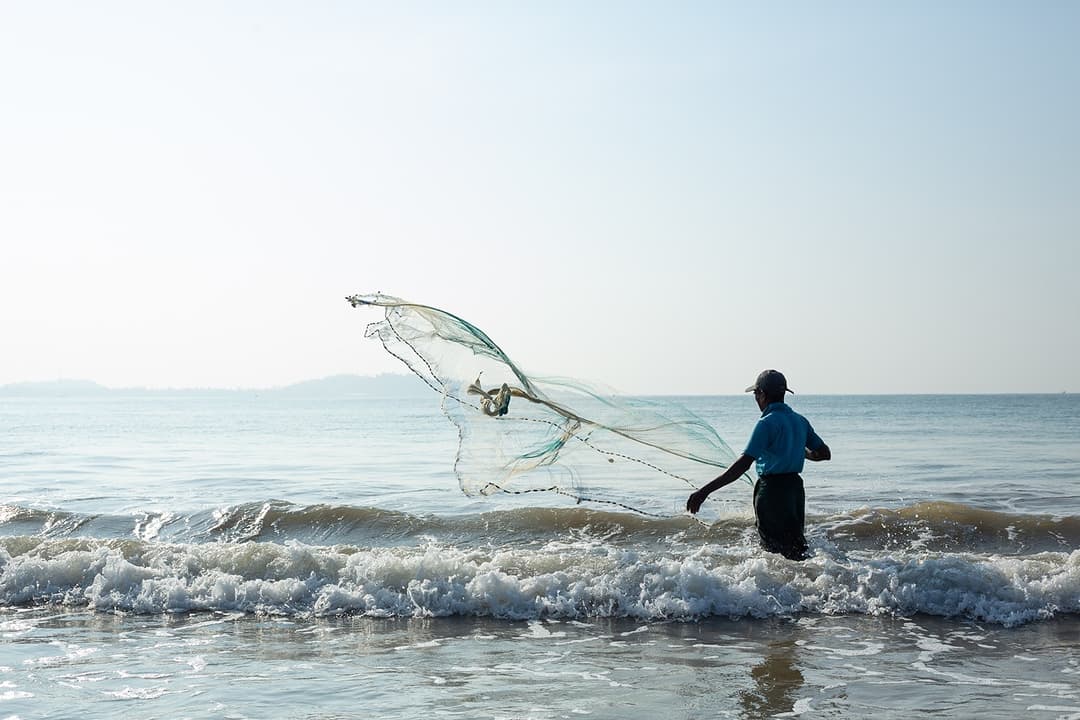 Sri Lanka stilt fisherman casting net in Indian Ocean near Mirissa