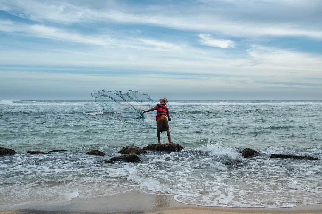 Sri Lanka stilt fisherman on rocky Thalaramba coast with Indian Ocean