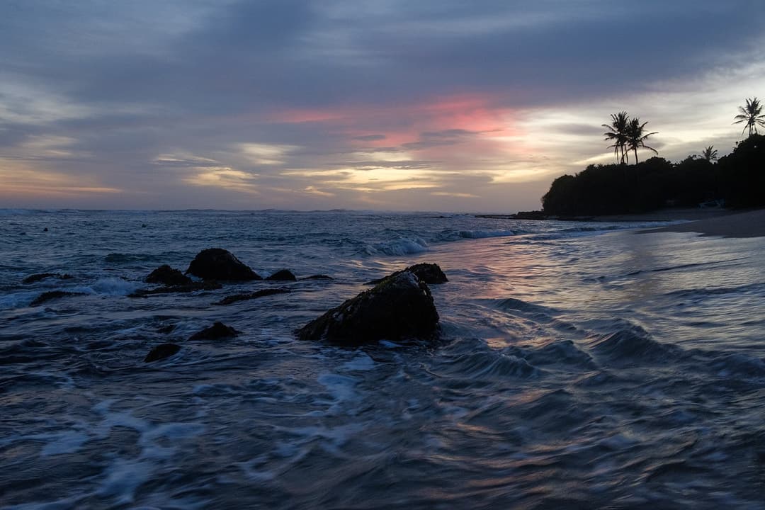 Dramatic sunset over rocky Thalaramba coast with orange sky Mirissa