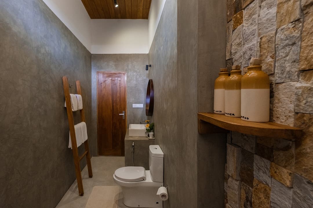 Mirissa villa bathroom with pebble stone wall and timber shelf