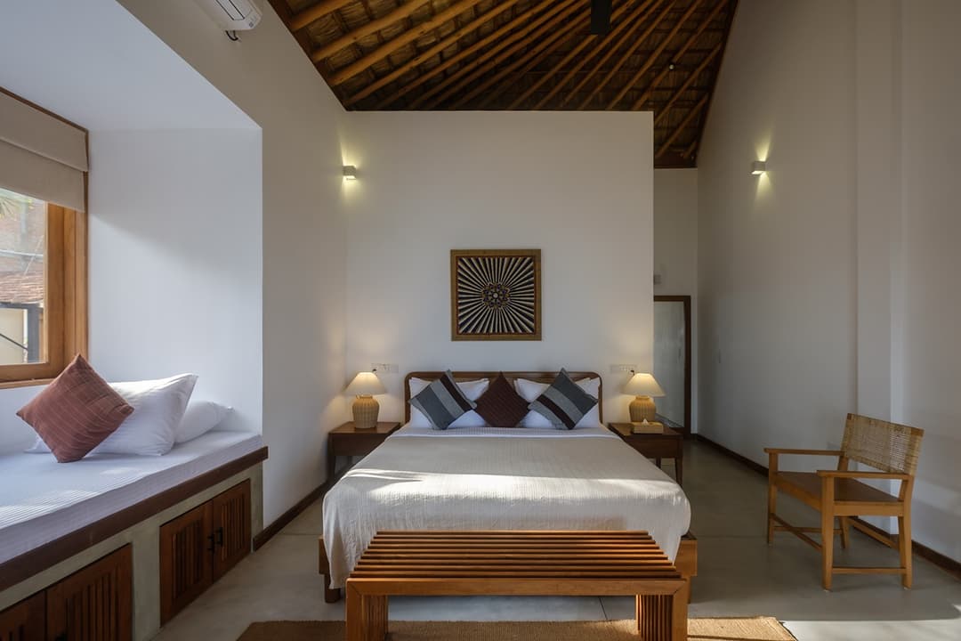 Mirissa villa bedroom with warm evening light and timber headboard