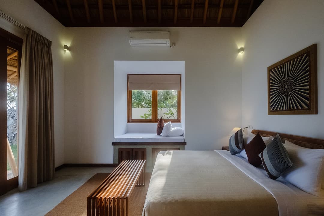 Wide angle Mirissa villa bedroom with thatched ceiling and artwork