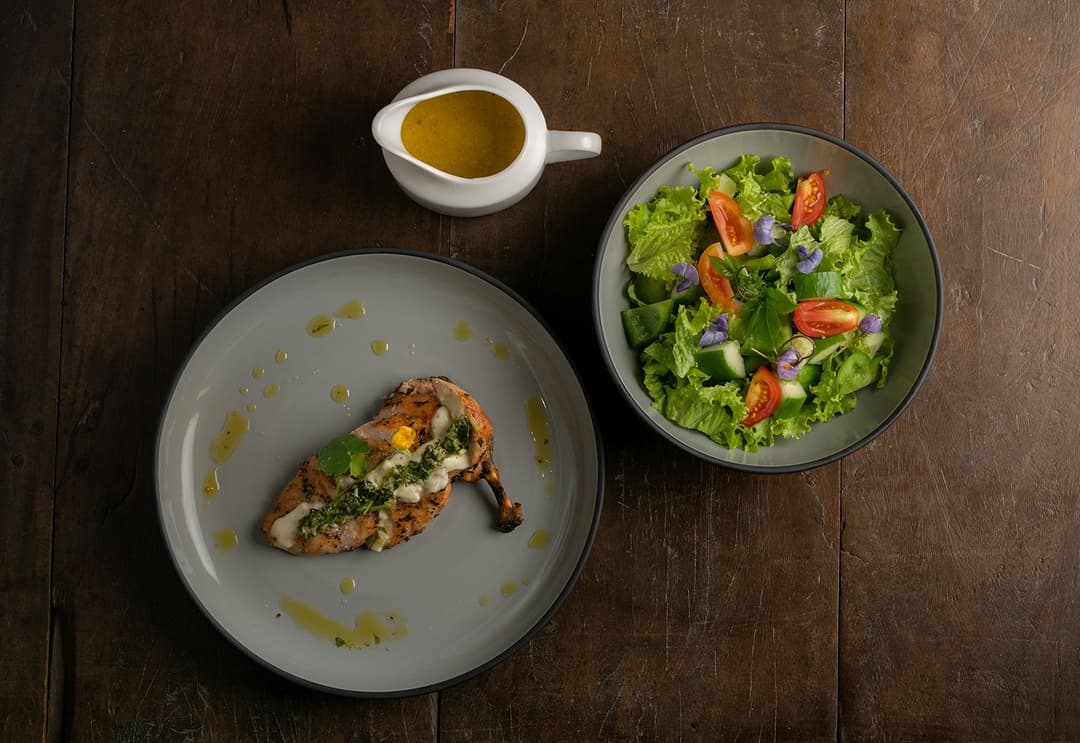 Villa chef plated fish and salad on dark timber table Mirissa