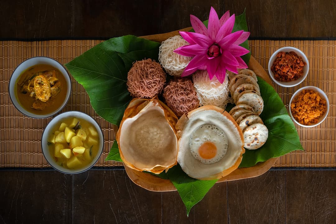 Overhead villa chef Sri Lankan breakfast spread with hoppers and roti on green leaf Mirissa