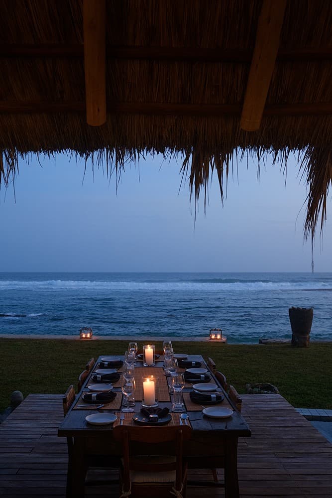 Mirissa villa outdoor dining with candles and ocean view at evening