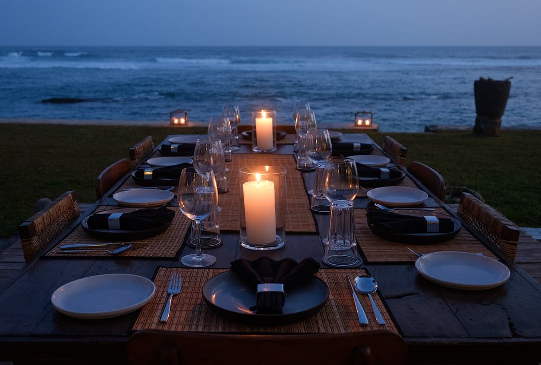 Mirissa villa outdoor dining table with candles under dark sky and ocean