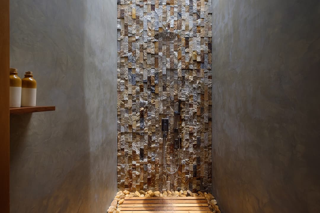 Close detail of Mirissa villa outdoor shower pebble stone feature wall
