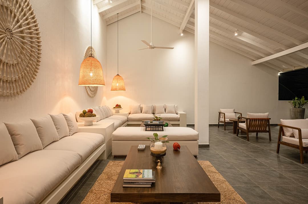 Wide view Mirissa luxury villa living room with white sofas and rattan artwork