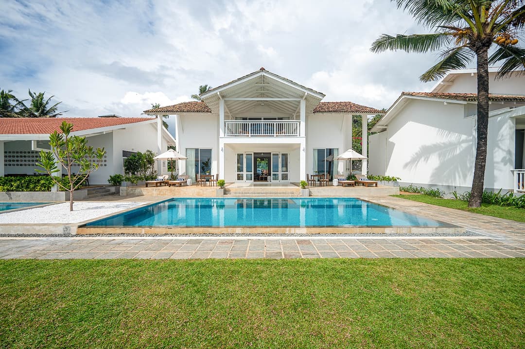 Sol House Mirissa exterior with pool, villa facade and palm trees daytime