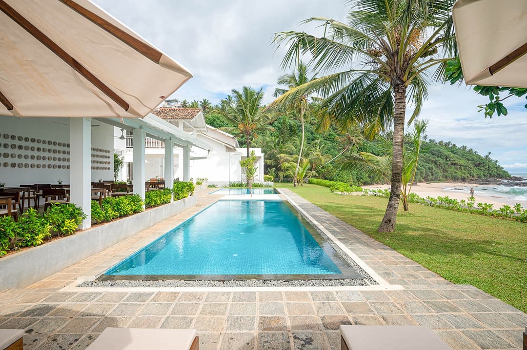 Sol House Mirissa long pool view with villa and tropical palm garden