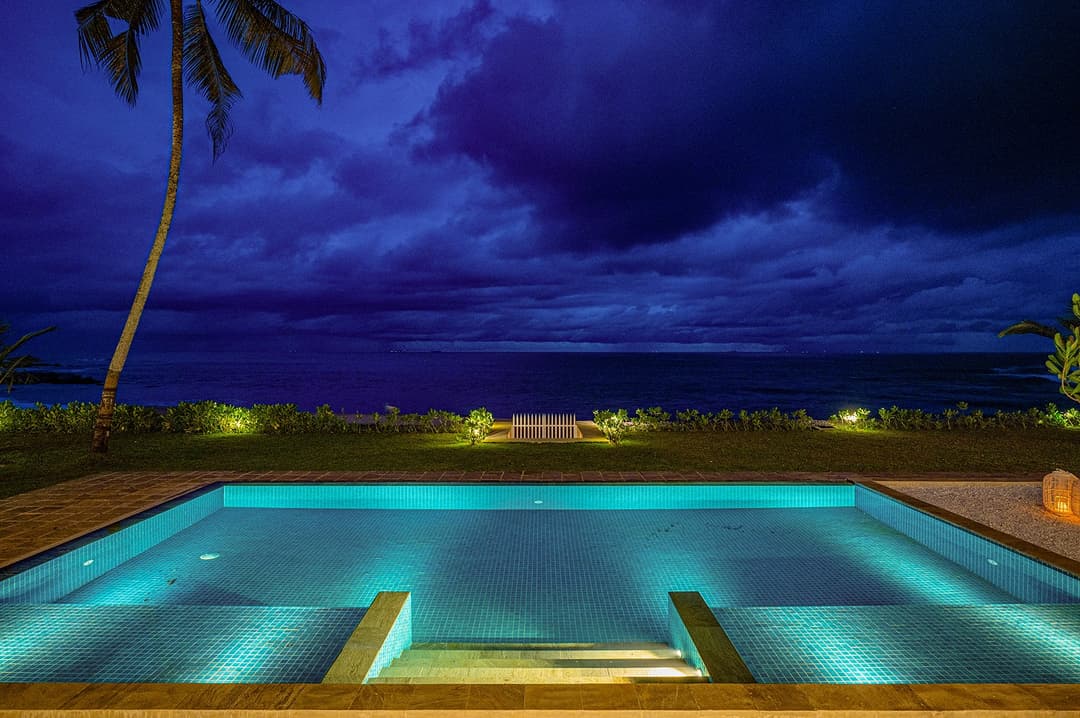 Sol House Mirissa pool at night with dramatic blue sky and palm silhouette