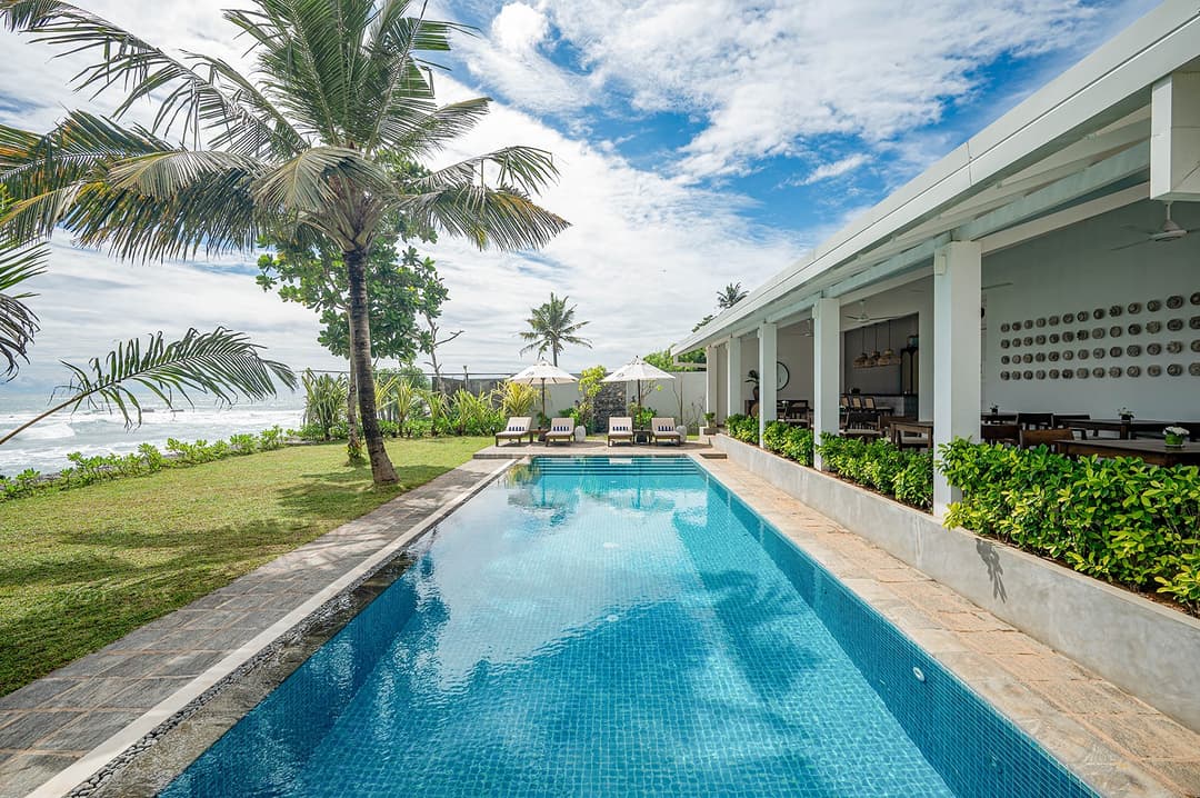 Sol House Mirissa pool with pavilion and palm trees under blue sky