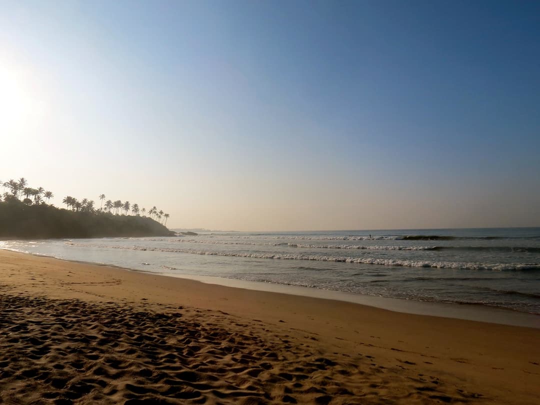 Matara beach at sunset with golden light and waves on sand