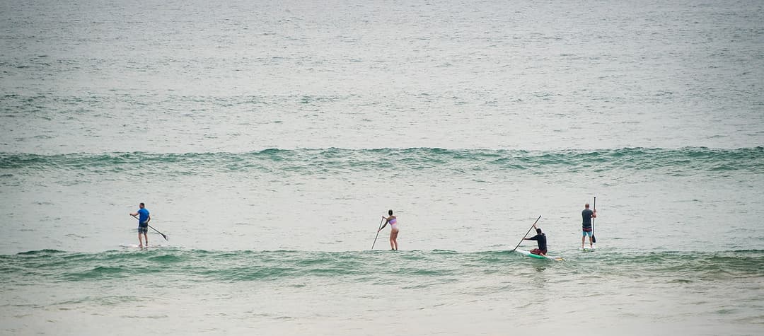 Surfers with paddle boards on gentle waves at Matara beach Sri Lanka