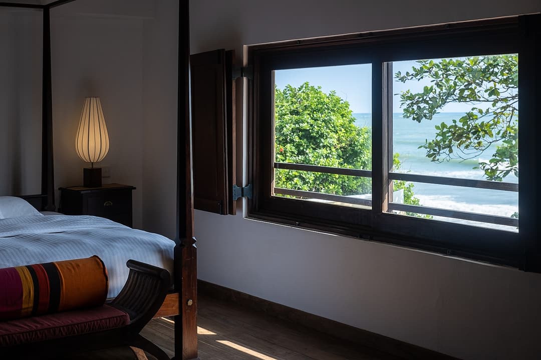 Matara villa bedroom with dark timber window frame and ocean view