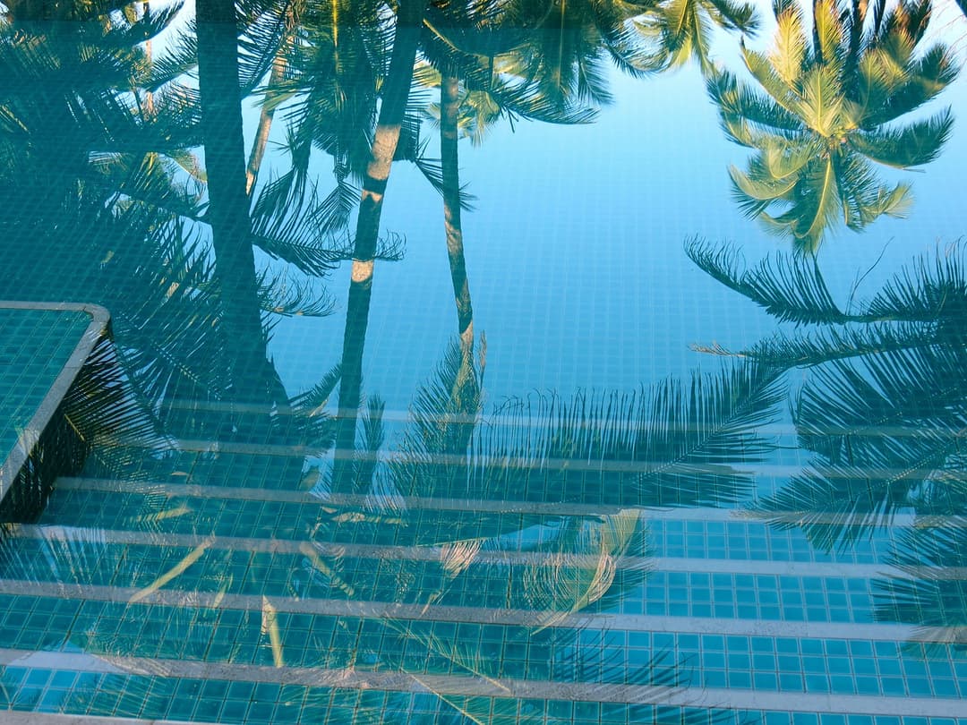 Matara villa pool reflecting palm trees and blue sky Sri Lanka