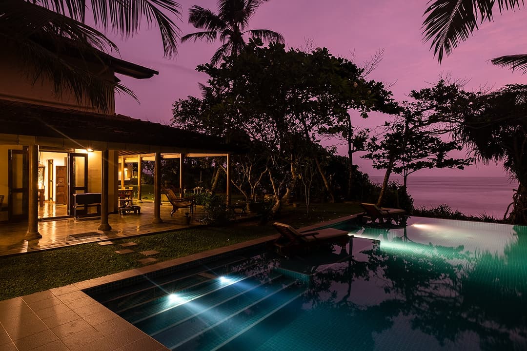 Villa Tres Matara infinity pool illuminated at evening with pink sky