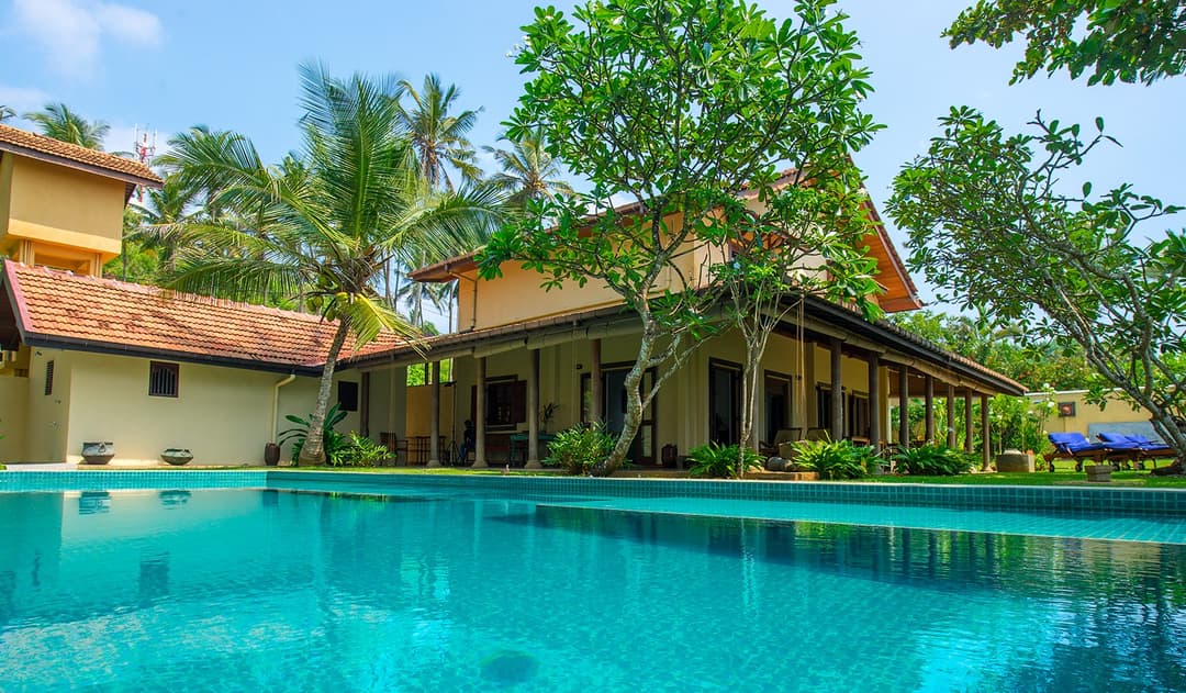 Villa Tres Matara pool with exterior facade and palm trees blue sky