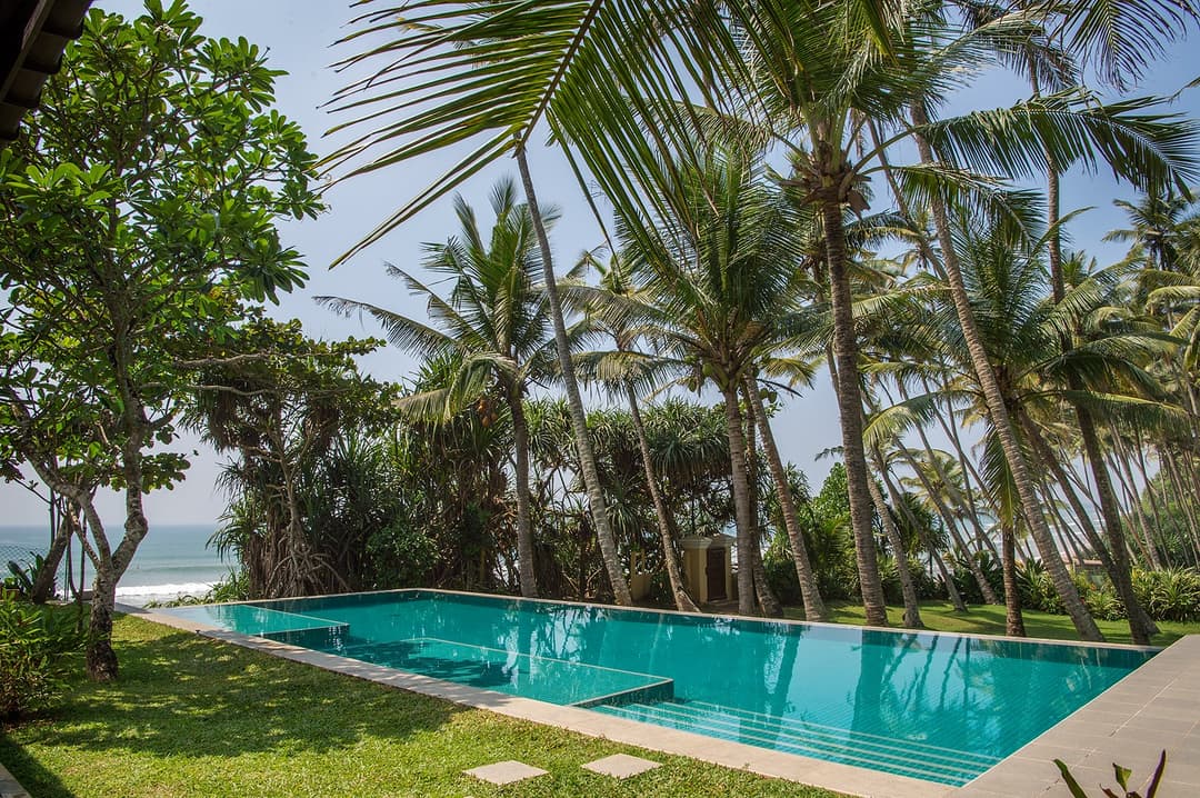 Villa Tres Matara pool with palm trees and tropical garden daytime