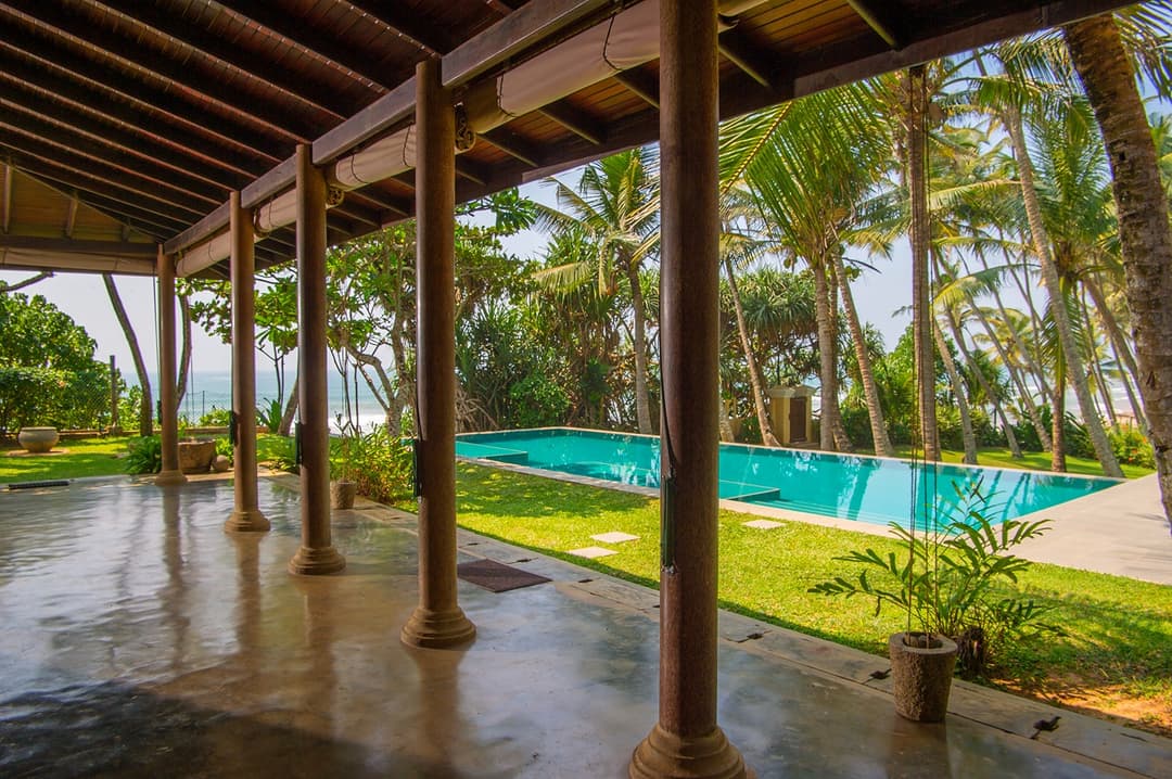 Villa Tres Matara pool with veranda columns and palm trees wide view