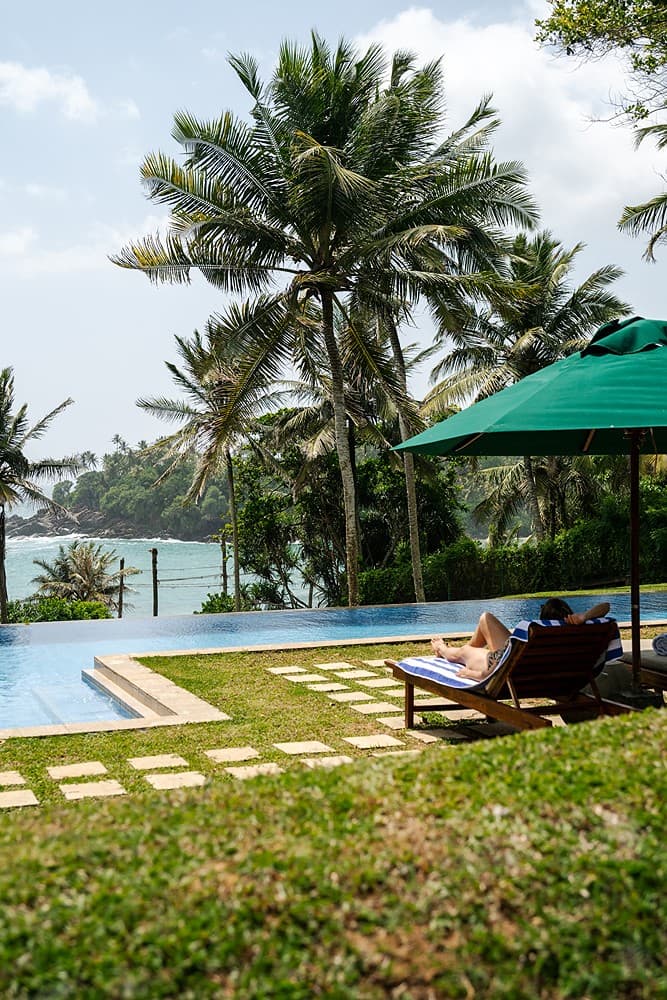 Wide-angle view of the expansive garden at Pavana Hiriketiya with towering palm trees and manicured lawn