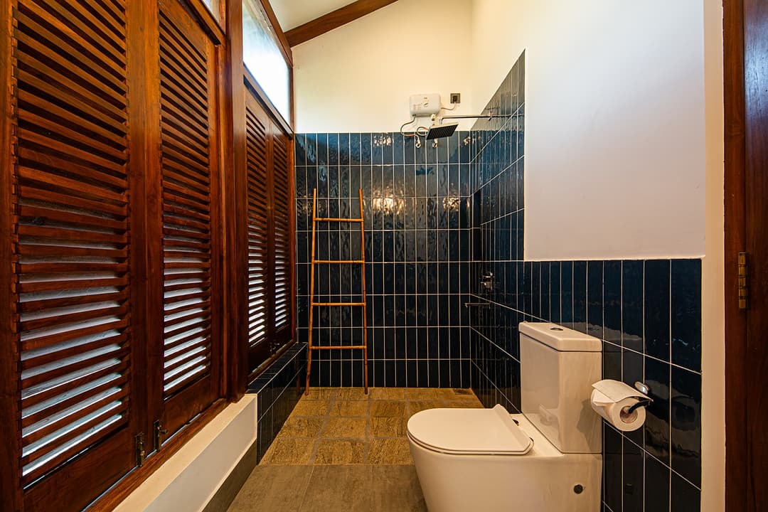 Villa bathroom with dark tiles and timber louvre shutters