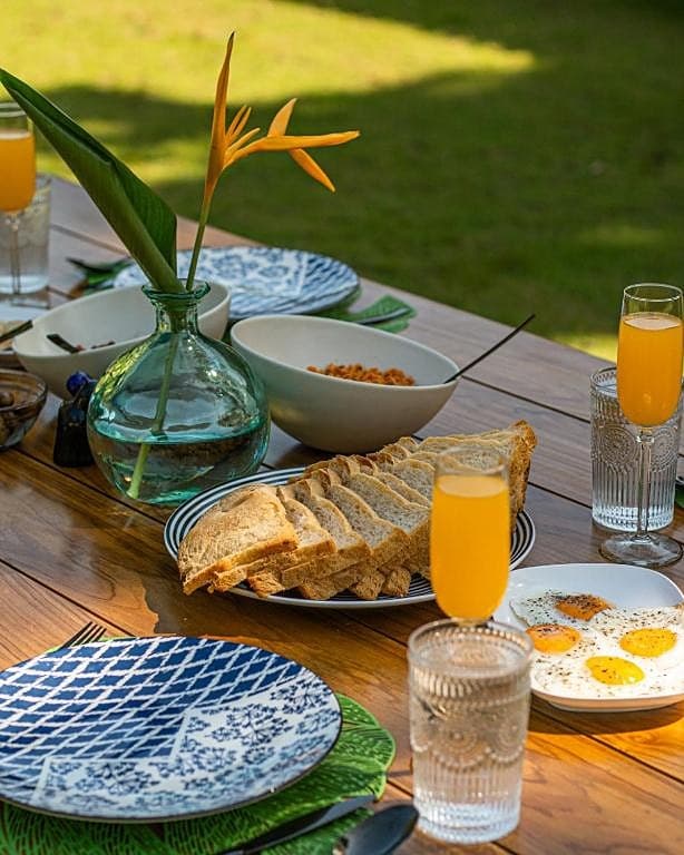 Outdoor breakfast spread on terrace table with tropical garden view