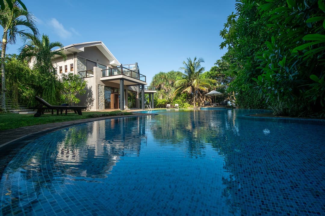 Casa Tua pool and garden with villa facade and palm trees