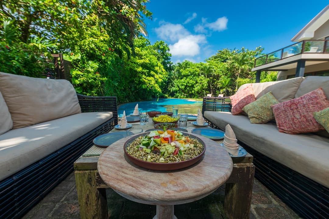 Casa Tua outdoor dining beside pool with evening garden view