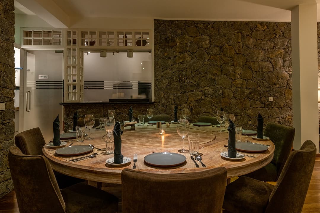Indoor dining table set for dinner with garden view beyond