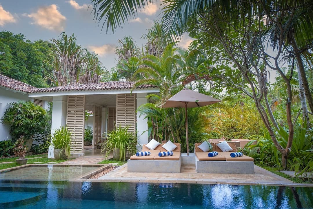 Rivers Edge pool and Dutch colonial villa facade with palm trees